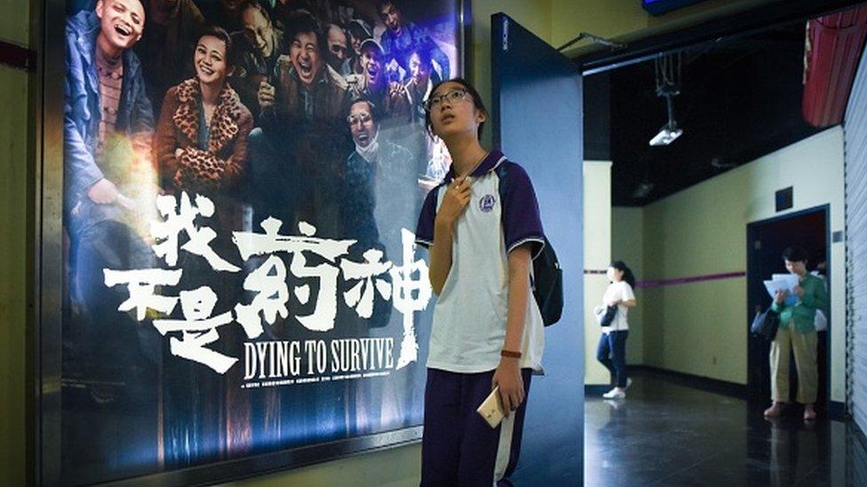 A young person in front of a 'Dying to Survive' poster