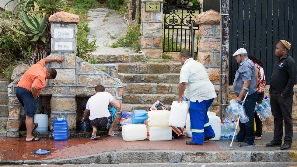 People collect drinking water from pipes fed by an underground spring, in St. James, about 25km from the city centre, on January 19, 2018, in Cape Town.