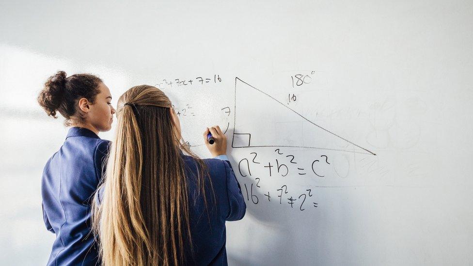 Two girls performing a calculation on a whiteboard