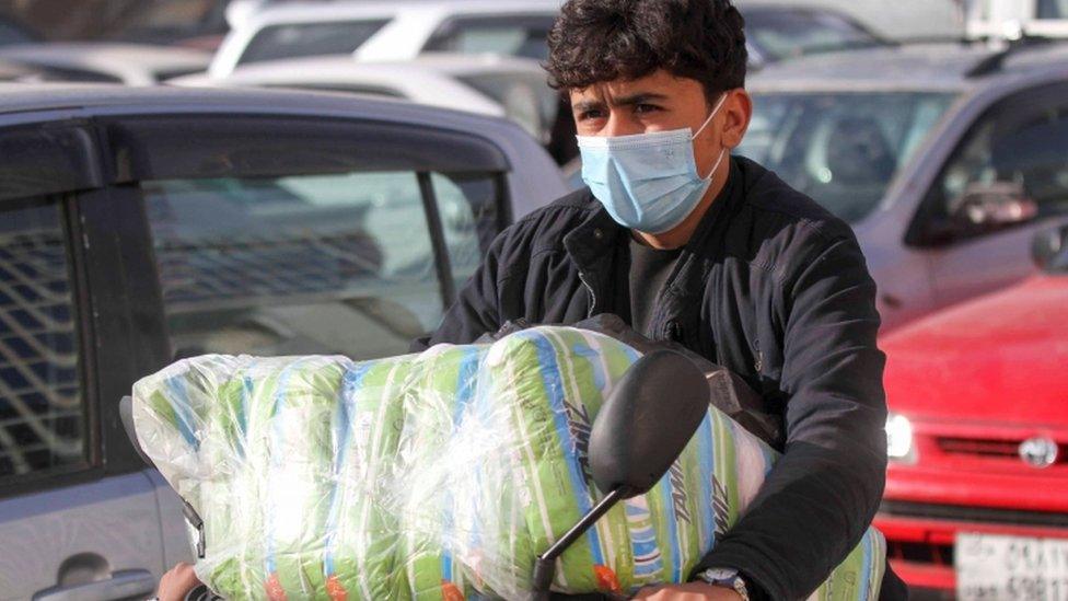 An Afghan man wears a face mask as he rides his motorbike in Herat province, Afghanistan