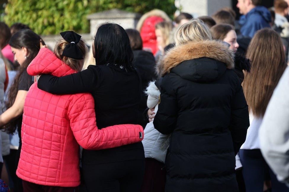 Friends of the family comfort each other at the vigil for the victims outside the family's home in Tallaght on Monday evening