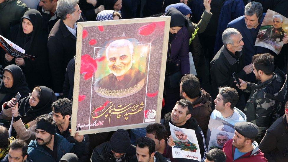 Mourners hold up pictures of military commander Qasem Soleimani during a funeral procession in Tehran, 6 January 2020