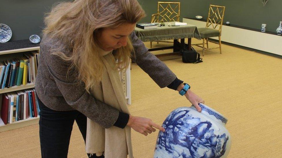 Katharine Butler holding one of the vases in the Butler Collection museum