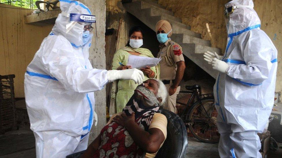 Health workers in PPE coveralls take swab samples from residents of Patiala.