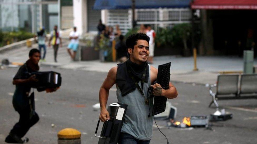 People run with looted items in Caracas. Photo: 19 April 2017