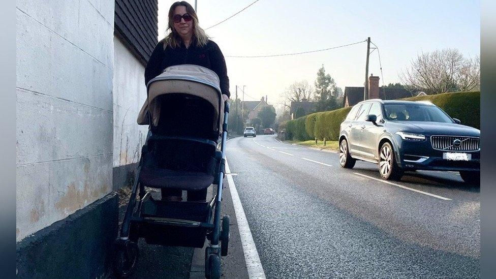 A woman with a pushchair on a narrow pavement