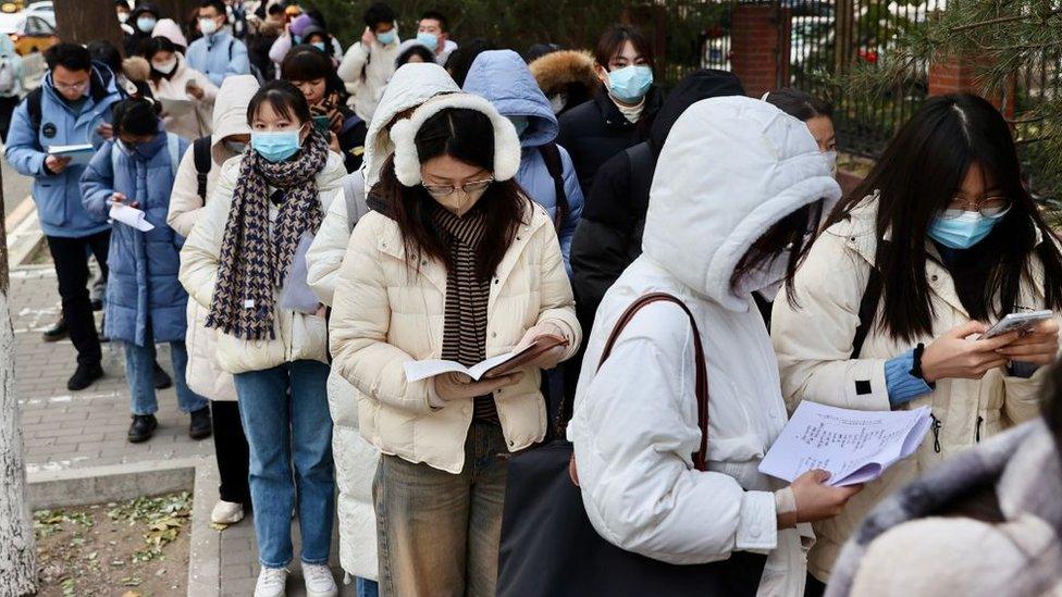 Examinees do last-minute revision before walking into an exam venue for the 2024 China's national civil servant exam on November 26, 2023 in Beijing,