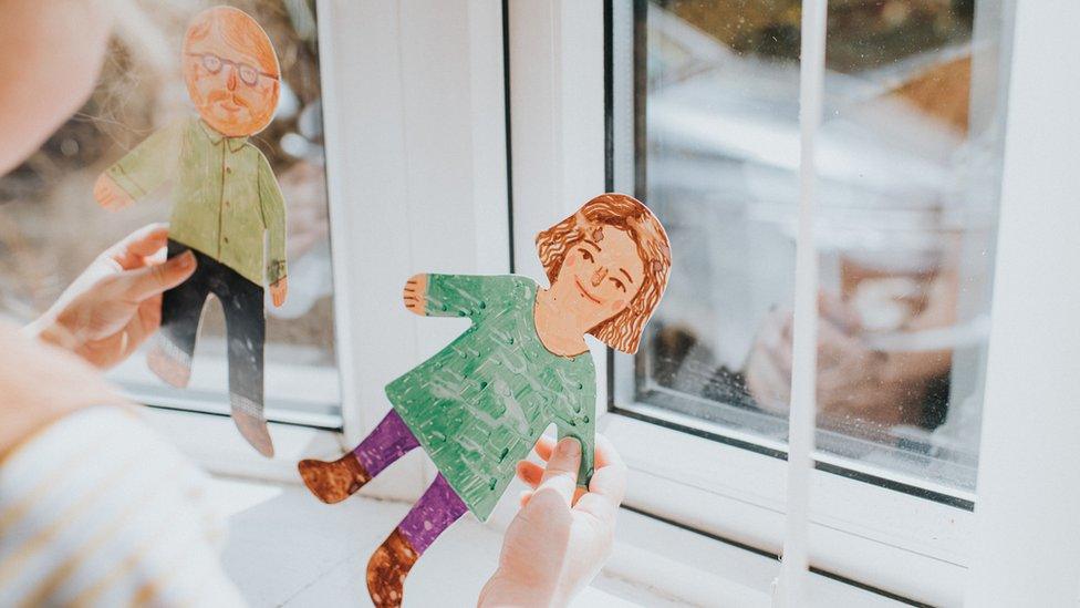 Girl holds paper models of parents