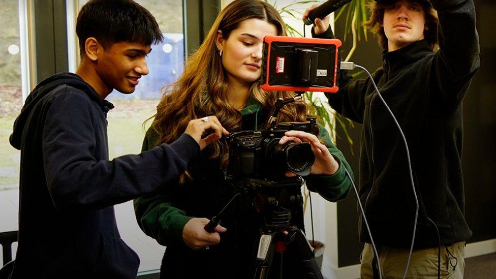 A group of three young people with a camera