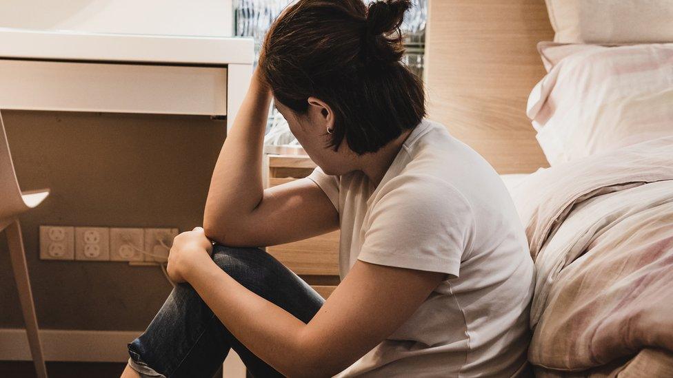 A depressed-looking woman holds her head while looking away