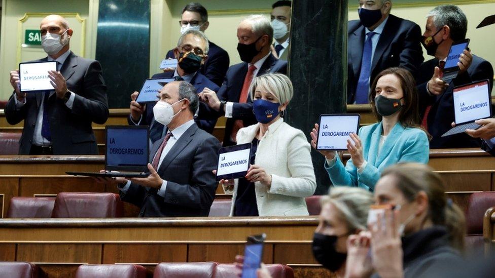 Members of far-right party Vox display electronic devices reading "We will repeal it" after the vote of the law on euthanasia