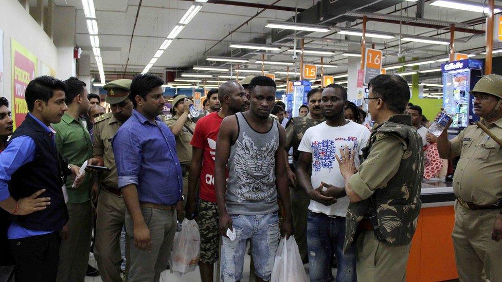 This photo taken on 27 March 2017 shows Indian police and onlookers surrounding African nationals at a shopping mall in Greater Noida