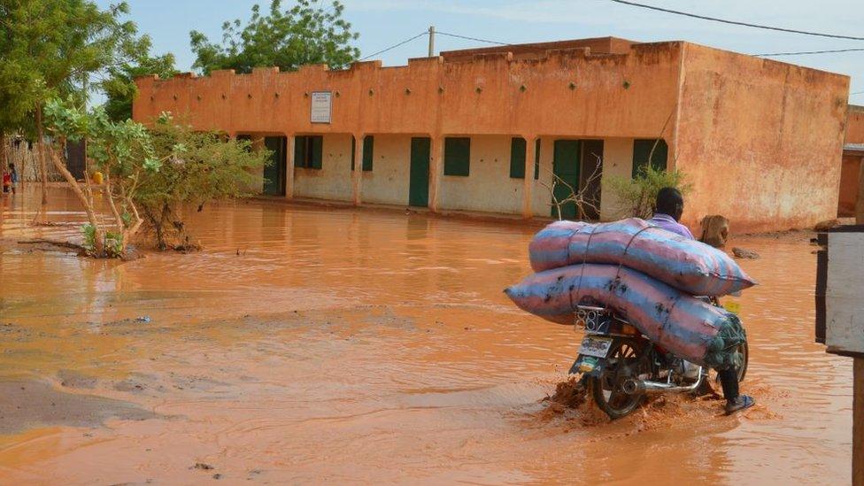 A man rides a motorbike with his belongings in a flooded street of Niamey following heavy rains, on June 15, 2017.