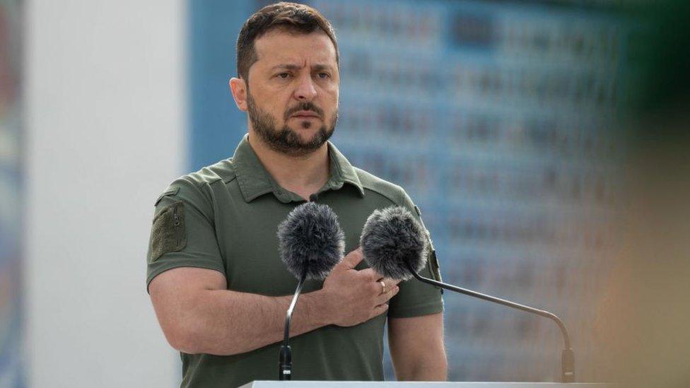 Volodymyr Zelensky standing behind a podium