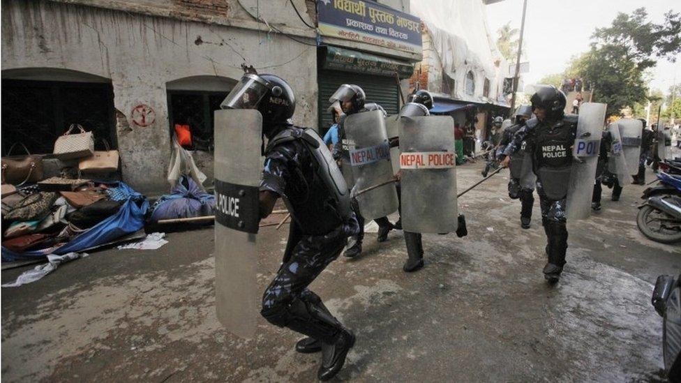 Nepalese policemen chase protesters after they burnt a copy of the new constitution during the protest organized by splinter of the Maoist party, alliance of ethnic group and Madhesi party, in Kathmandu, Nepal, Monday, Sept. 21,2015