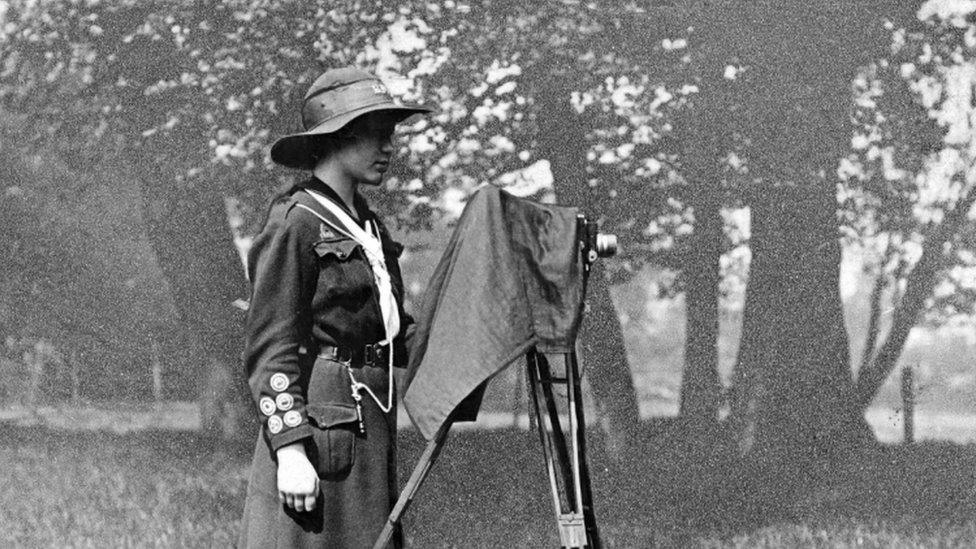 A girl guide from 1912 is completing her Photographers' Badge