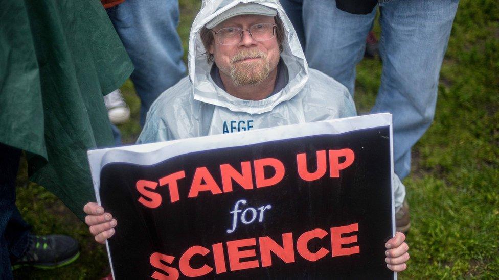 A man with a Stand Up for Science banner