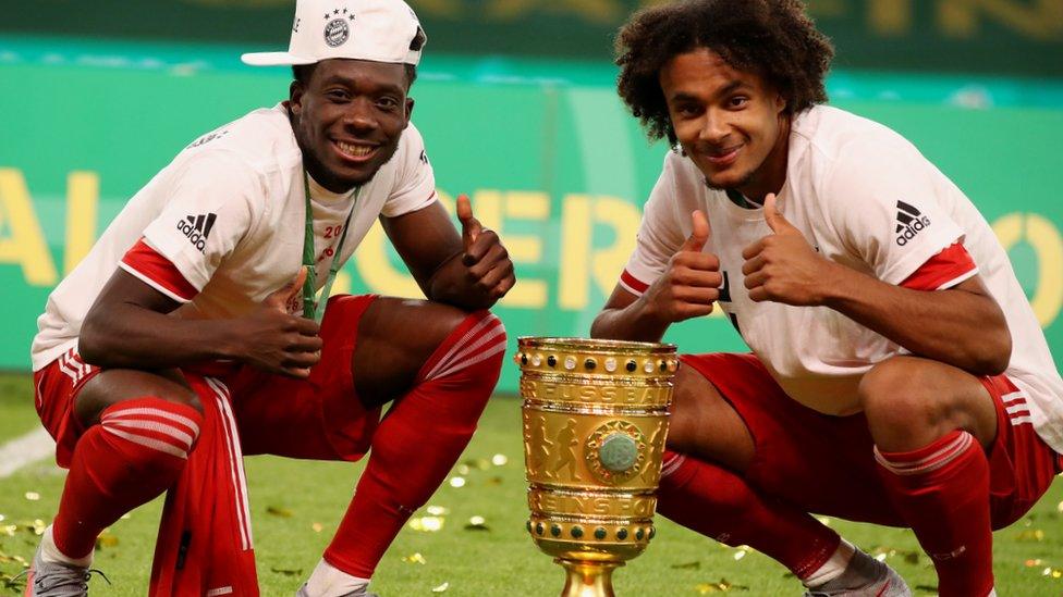 Alphonso Davies and Joshua Zirkzee celebrate with the trophy after winning the DFB Cup