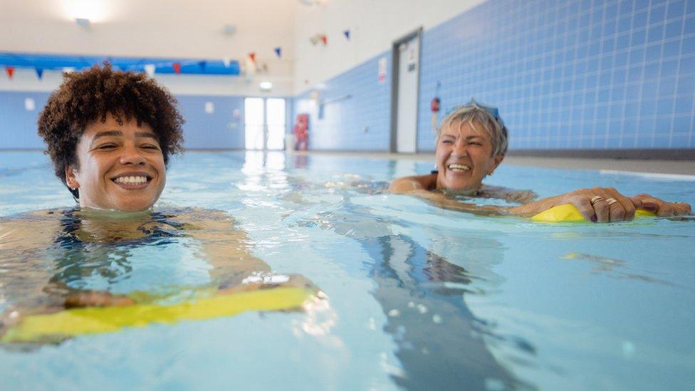 Two women in a pool with flutter boards