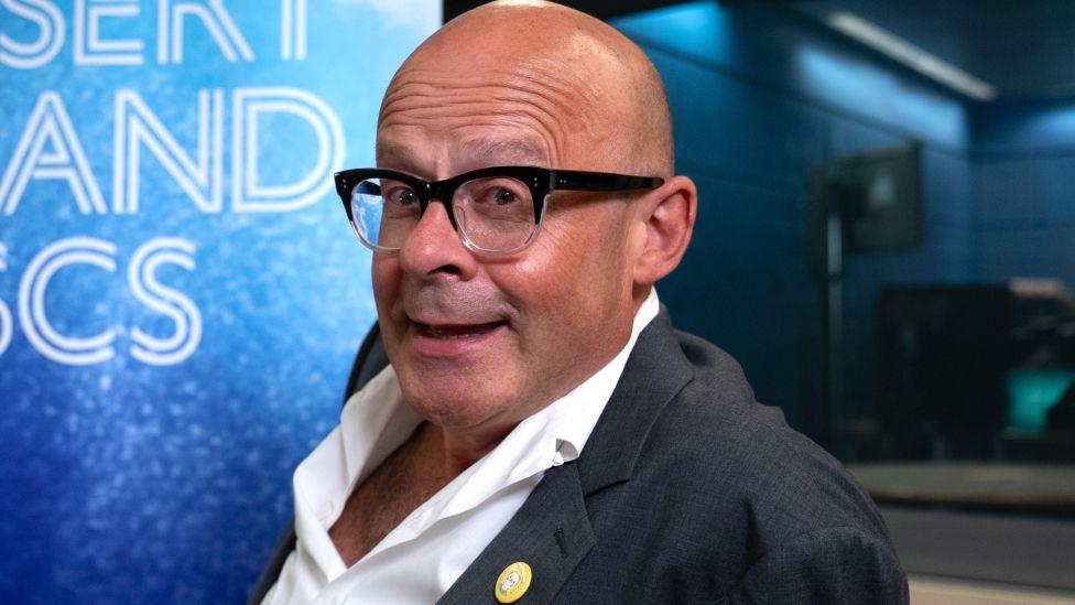 Harry Hill in the Desert Island Discs studio, wearing a suit with an open-collar shirt