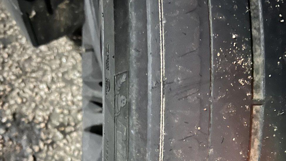 A close-up photograph of a car tyre showing it is very worn