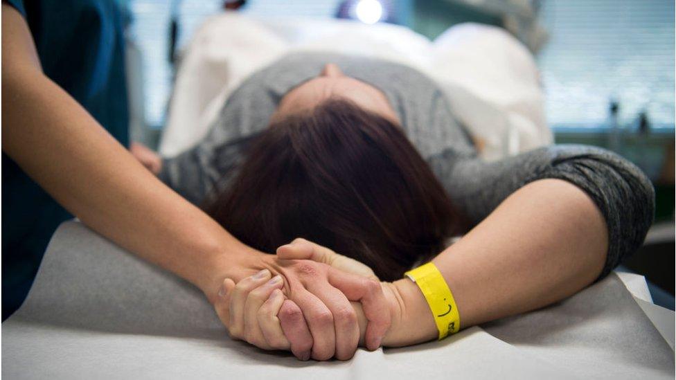 An abortion doula holds hands with a patient during an abortion procedure at an abortion clinic