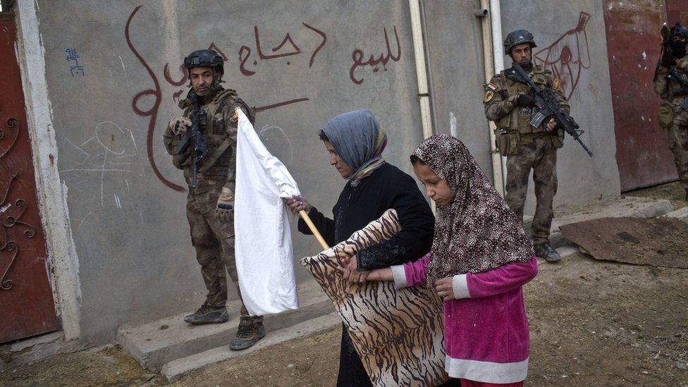 Civilians carry a white flag as they pass by Iraqi special forces on patrol, 2 November 2016