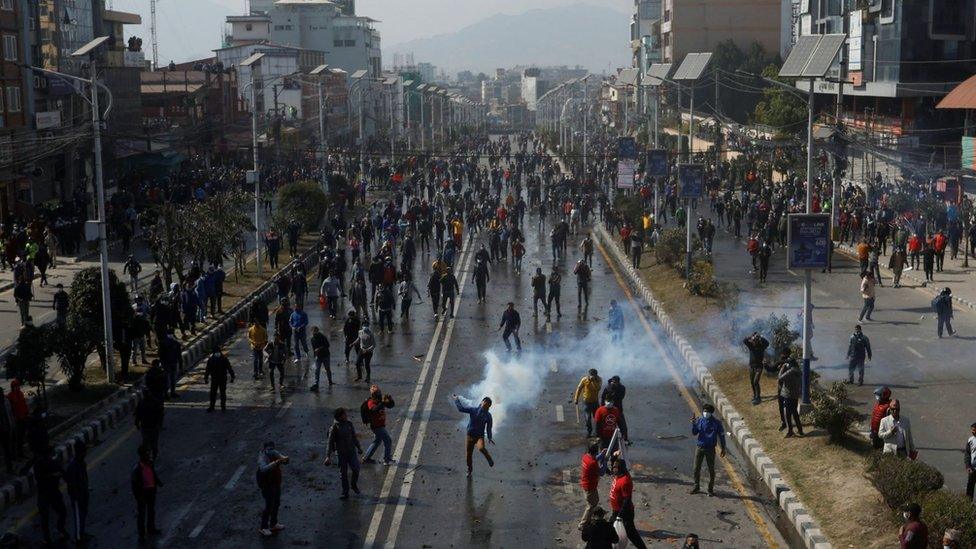 A demonstrator throws a tear gas cylinder back at police in Kathmandu