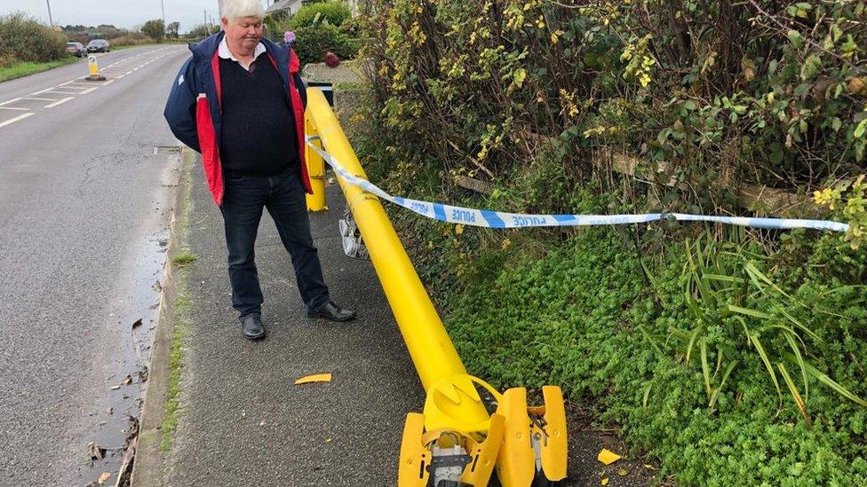 Mabe parish councillor Peter Tisdale next to the chopped down speed camera