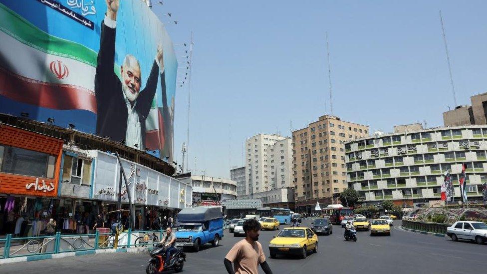 Cars and people on a street in Tehran with a large billboard showing an image of former Hamas leader Ismail Haniyeh (file photo)