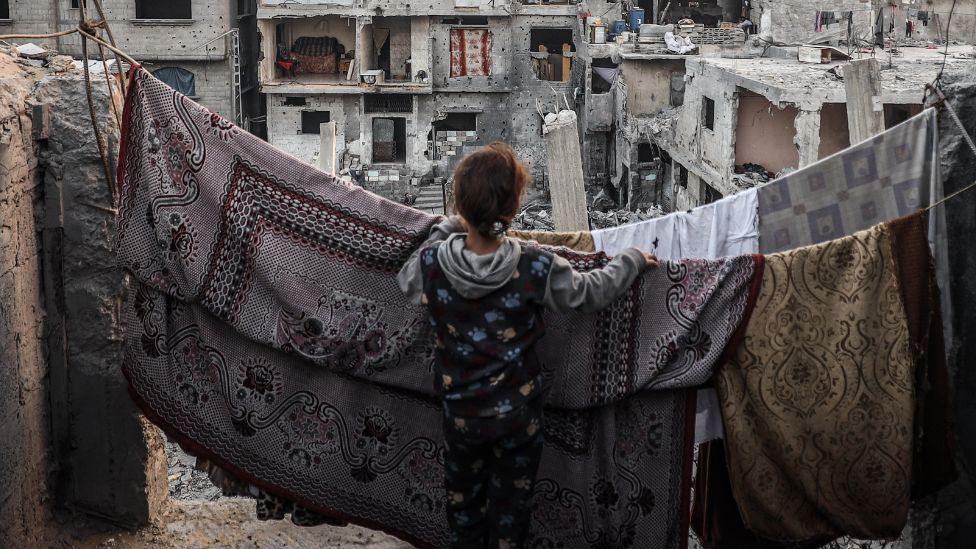 A children standing in front of a clothes line, overlooking buildings in Gaza. 