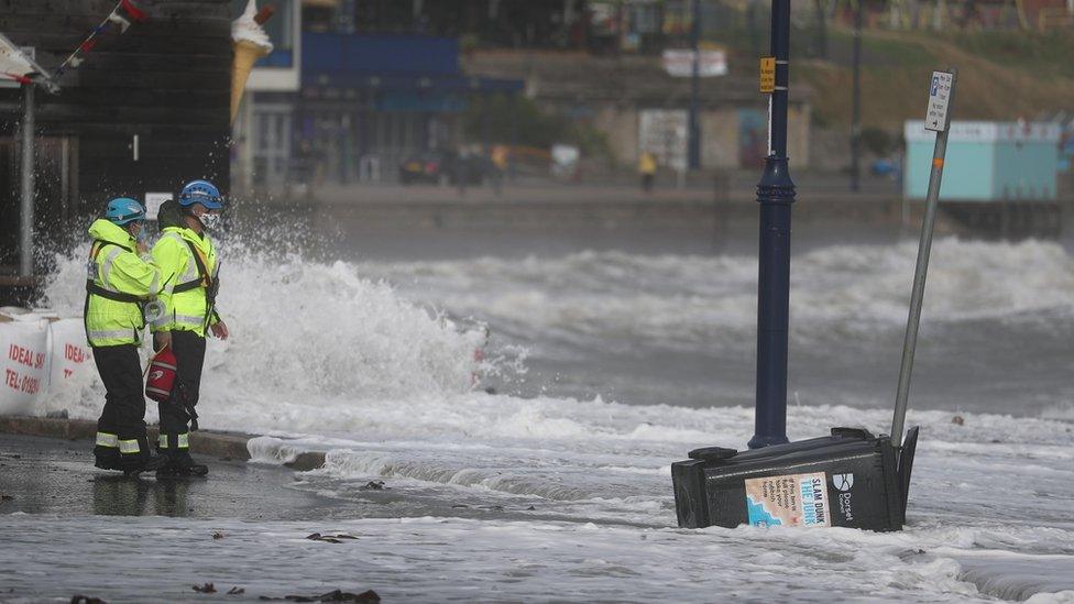 Members of the Coastguard watch as waves crash along the coast at Swanage