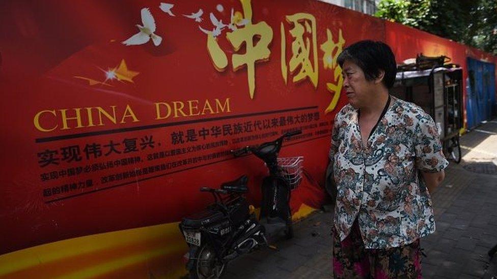 A woman looks at a banner about the 'China Dream', Chinese President Xi Jinping's vision for China's future, in Beijing on July 7, 2015