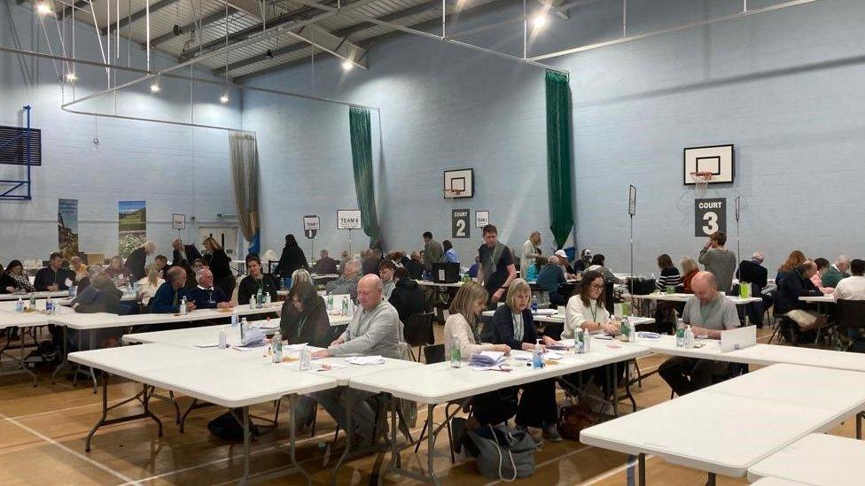 Volunteers counting votes in a sports hall