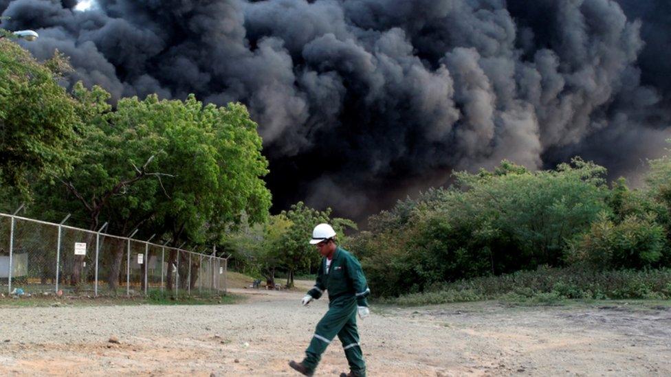 A man walks near an explosion caused by a fire at a fuel storage tank belonging to the Puma Energy company in Puerto Sandino Nicaragua 2016.