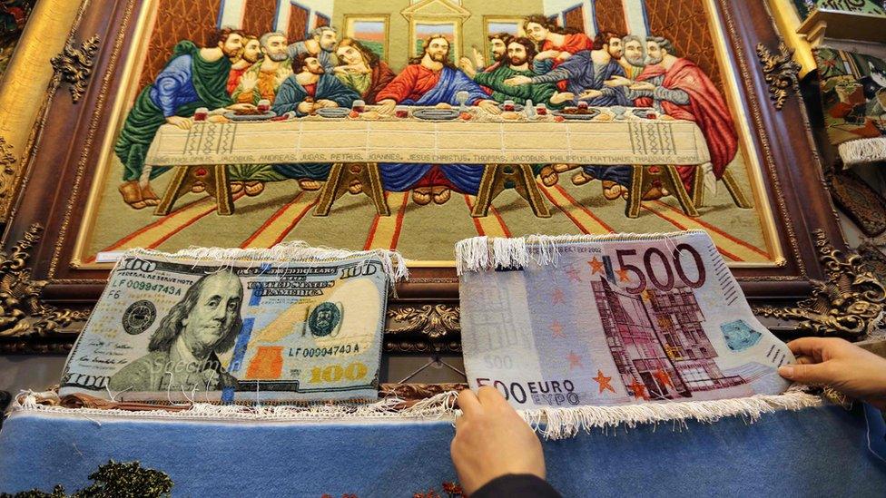 An Iranian vendor displays carpets at his shop in Tehran's Grand Bazaar on 16 January 2016