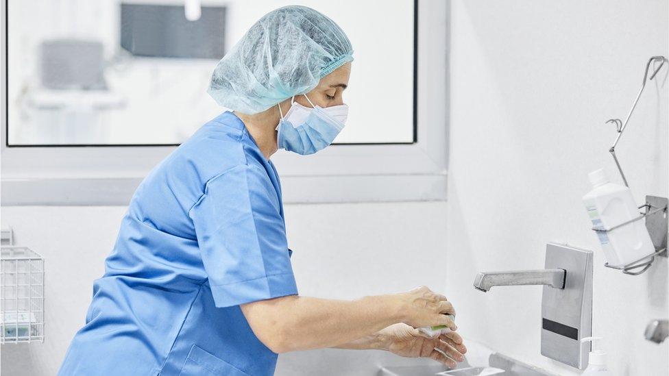 female doctor washing hands with soap at hospital.