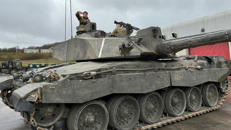 Noah standing up in a tank and saluting