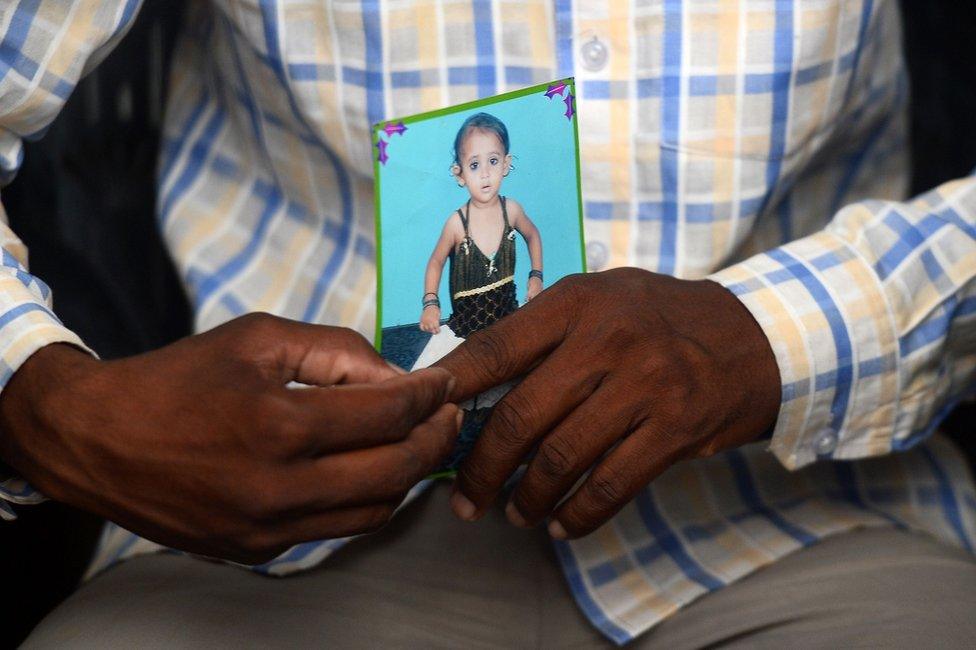 Mohamed Zahid hold a photo of his five-year-old dauhter, Khushi, in a black dress