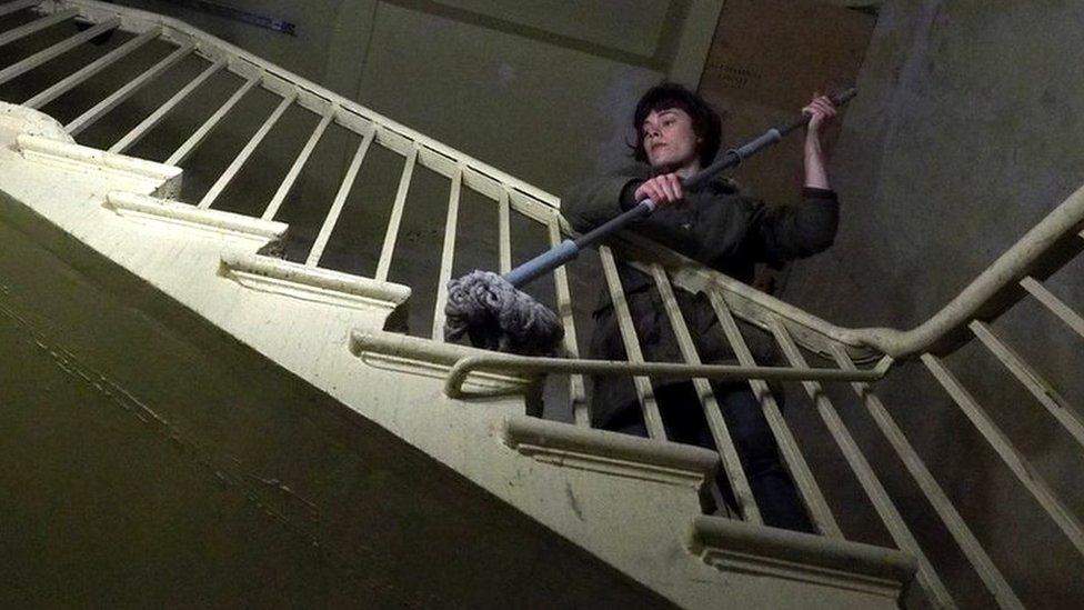 A woman cleaning a staircase with a mop