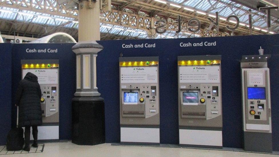 A woman queues at a ticket machine