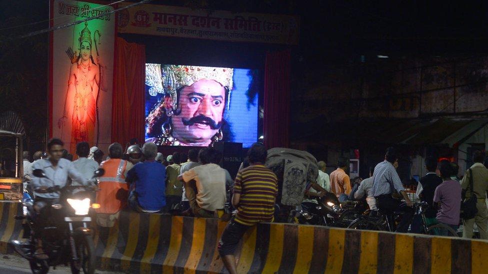 People sit along the road side watching an Indian epic television series of Ramayana, the story of the battle of Hindu god Rama over the demon king Ravana, as they celebrate Navratri (Nine Nights) culminating on the tenth night with the Dusshhra festival depicting the victory of Good over Evil, in Allahabad on September 25, 2017