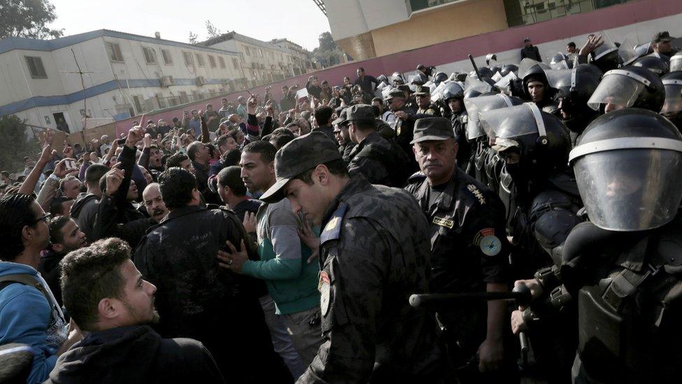 Coptic Christians protest as police stand guard at the Virgin Mary Church in Cairo, Egypt, following a funeral service for victims of a Sunday cathedral bombing, 12 December 2016