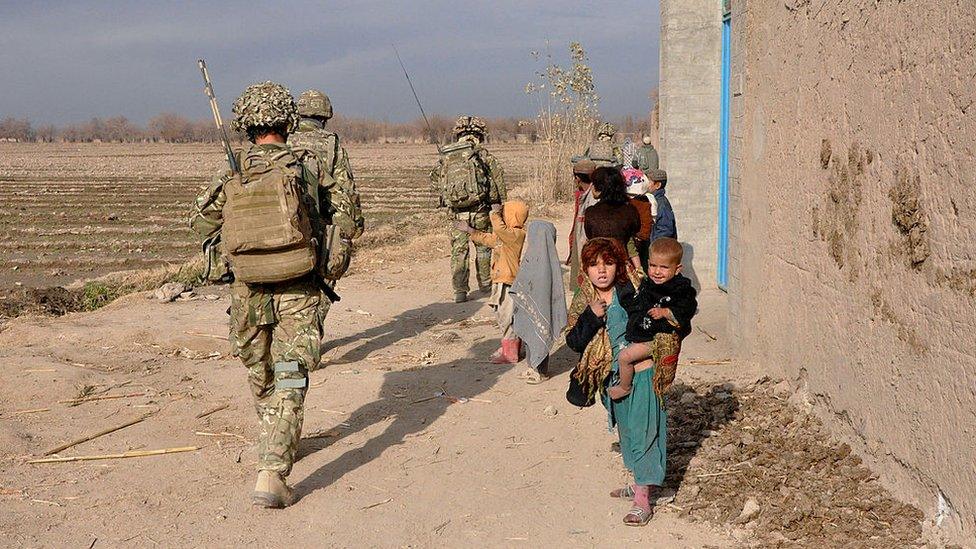 British soldiers pass by local children on route to a patrol base in Helmand province.