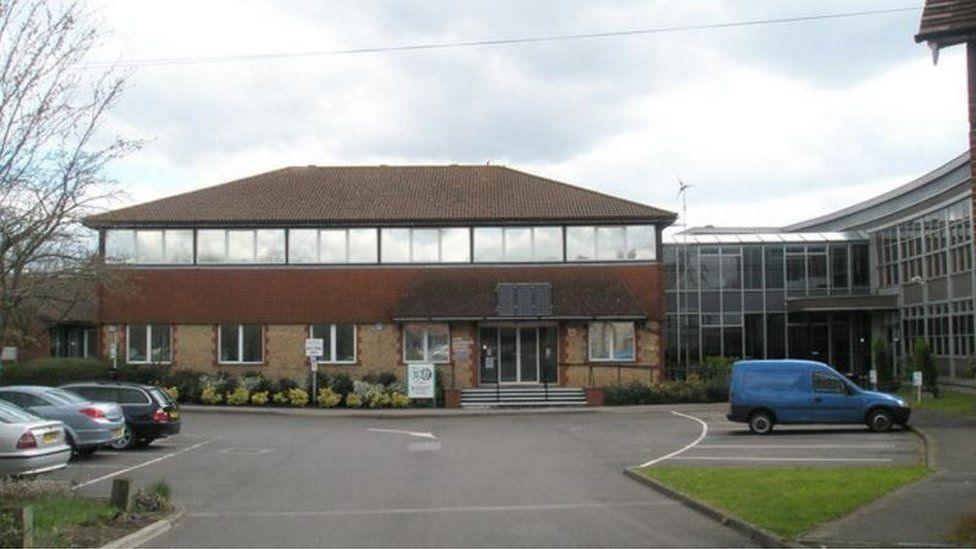 East Hampshire District Council building photographed on a cloudy day. Four cars are parked in front.