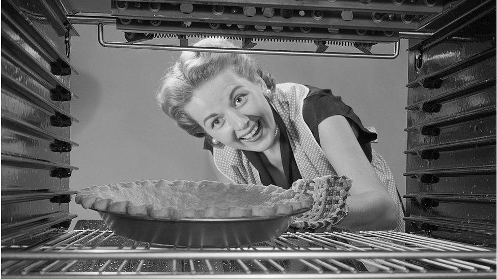 Woman looking at pie in oven