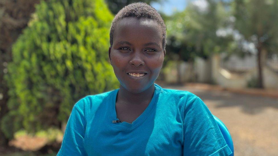 A woman in a blue t shirt smiles at the camera