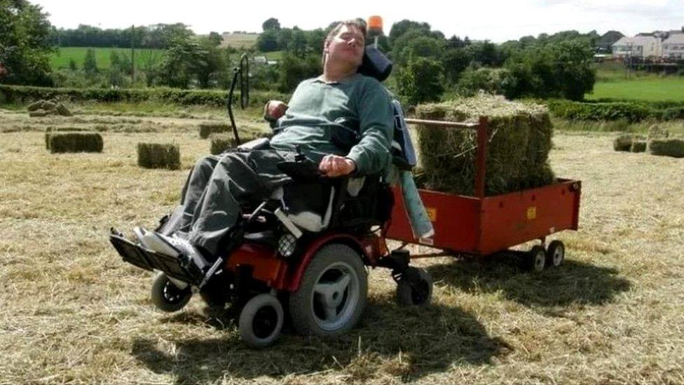 Jonathan Turtle uses his wheelchair to tow a trailer containing hay bales