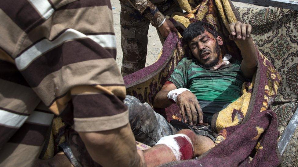 Iraqi security forces carry an injured man on a blanket as they evacuate civilians from the Old City of Mosul (3 July 2017)