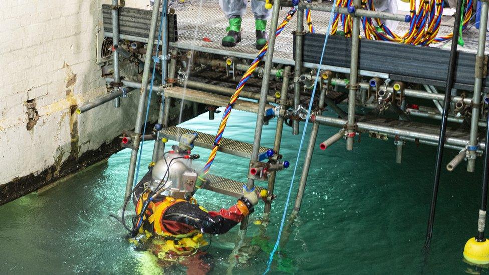 A diver climbs a ladder into a bright blue pool